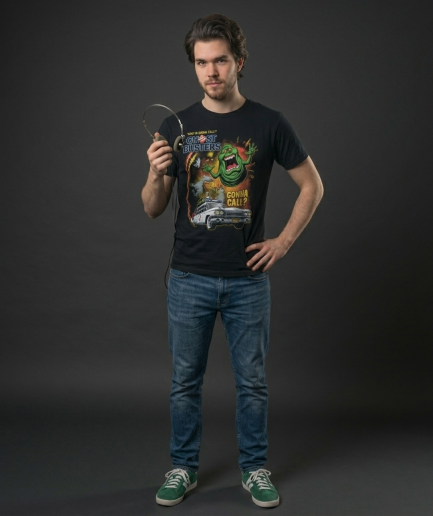 T-shirt nera Ghostbusters con Slimer verde e macchina Ecto-1 su sfondo neutro professionale.